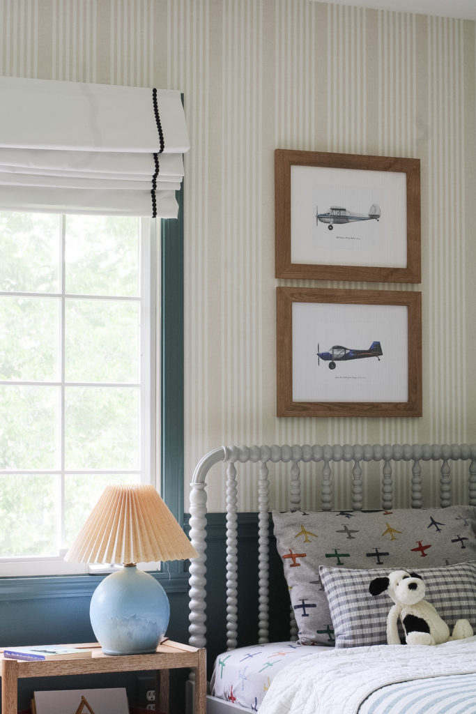 The walls are painted sherwin william's riverway on the lower half and above the chair rail is a linen stripe wallpaper. Airplane illustrations hang on the wall above a gray Crate & Barrel Jenny Lind bed with airplane sheets.