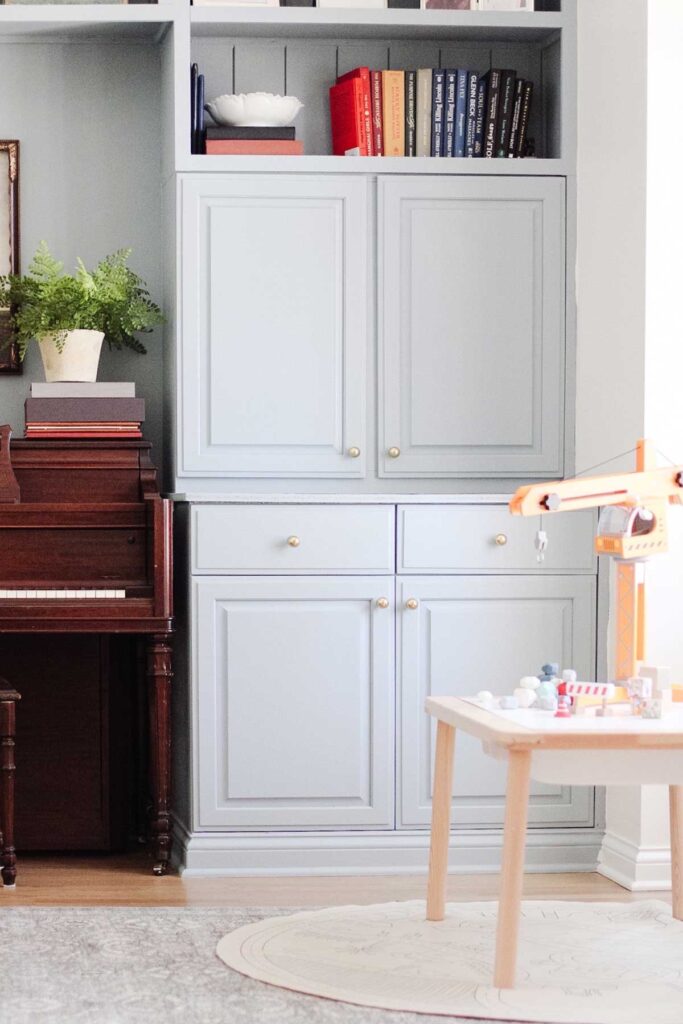 piano surrounded by cabinets painted in Sherwin William Debonair, blue with a toy crane on a table in front