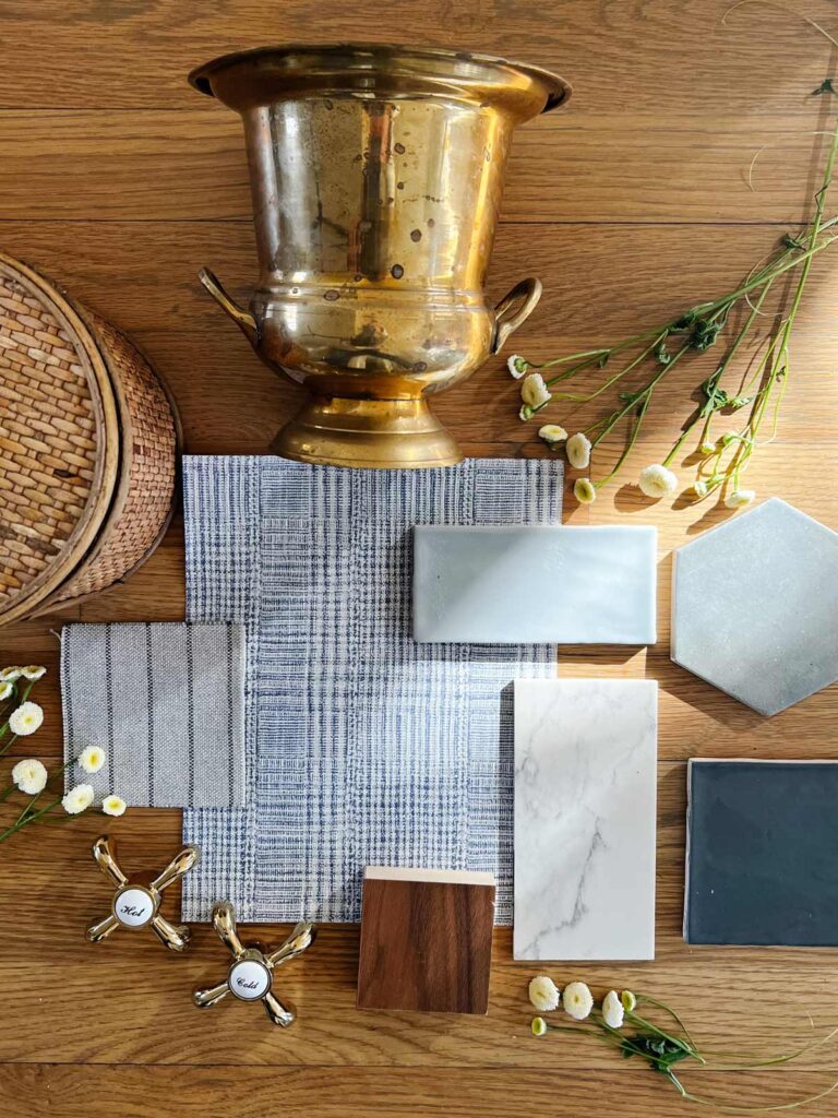 flatlay of bathroom design materials including blue subway tile, blue hexagon tile, walnut wood, quartz countertop, and plaid wallpaper