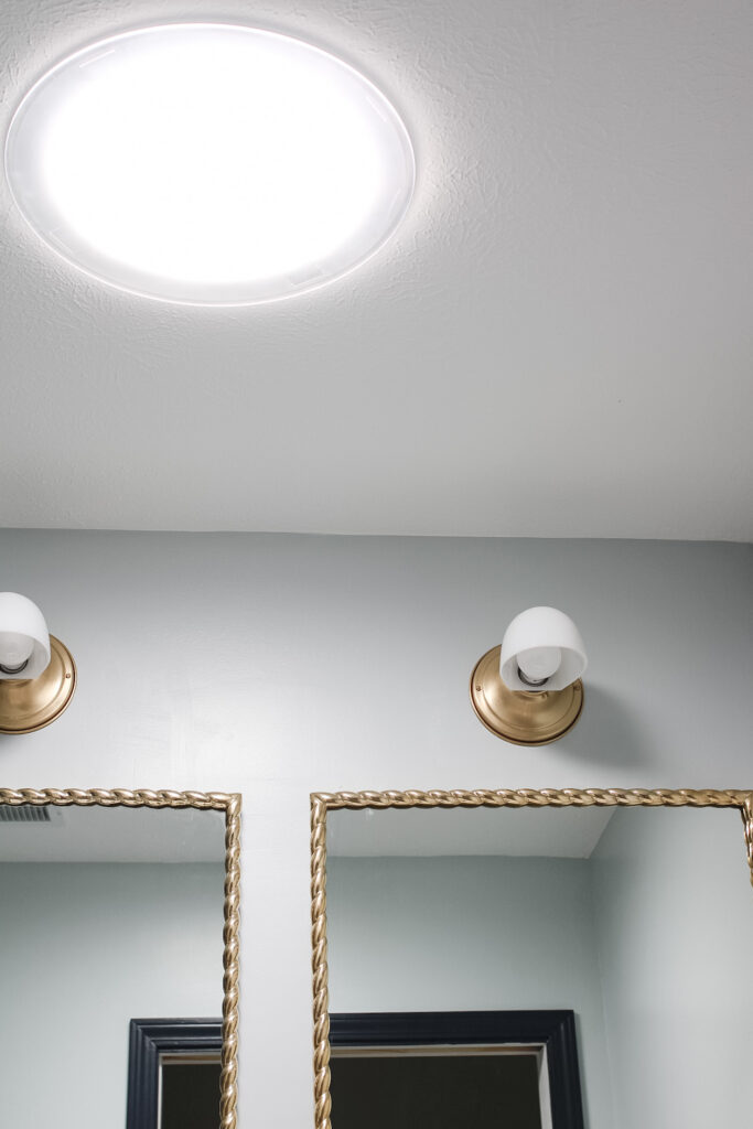 A 14" velux sun tunnel diffuser in a bathroom over a vanity with double lights and mirrors. 