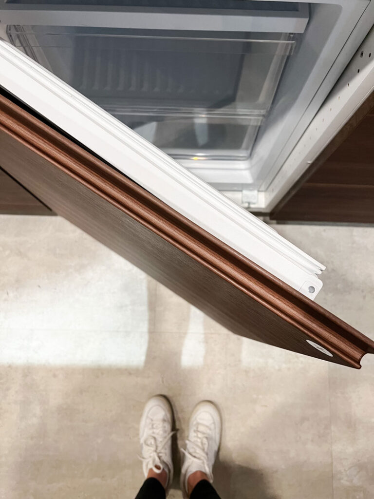 an in store display of the ikea voxtorp  walnut effect cabinet series door opened to show the edge finger pull