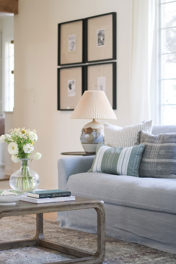 blue linen sofa with a coffee table that has flowers on it in front of it.